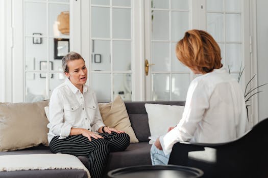 Two women having an intimate conversation on a sofa in a cozy indoor setting.